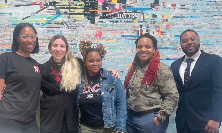 A photo of four educators from Woodson High School in front of a colorful backdrop